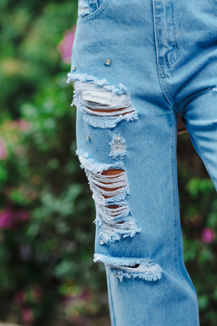 Fashionable ripped denim jeans with embellished details in an outdoor setting.